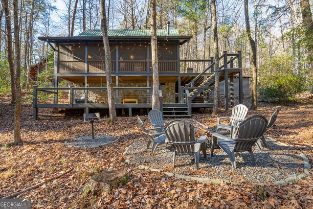 rear view of property with a sunroom, a fire pit, and a deck