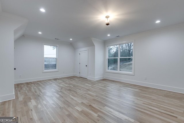 additional living space with light hardwood / wood-style flooring and lofted ceiling