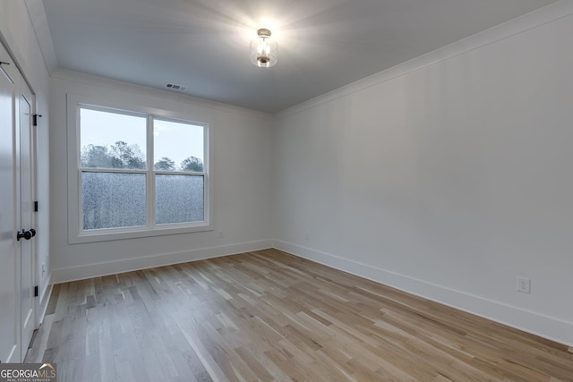 empty room featuring light hardwood / wood-style floors and crown molding