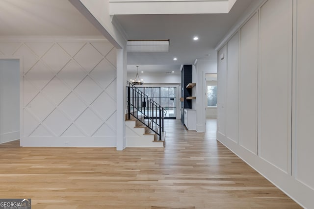 corridor featuring light wood-type flooring and a notable chandelier