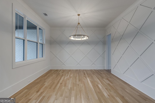 unfurnished dining area with ornamental molding and light hardwood / wood-style flooring