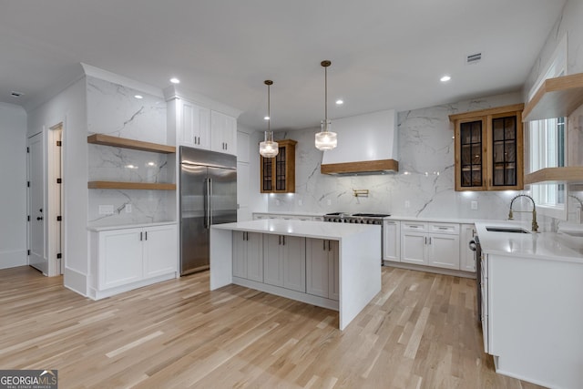 kitchen with a center island, stainless steel built in fridge, sink, custom range hood, and white cabinetry