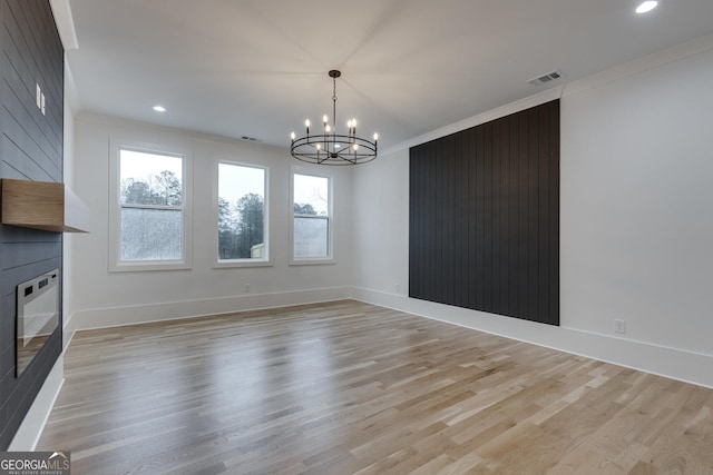 unfurnished dining area with crown molding, light hardwood / wood-style flooring, and an inviting chandelier