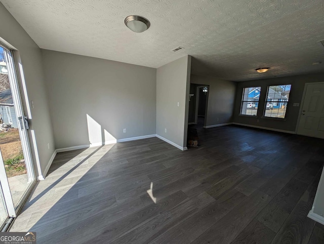 unfurnished living room with a textured ceiling and dark hardwood / wood-style floors