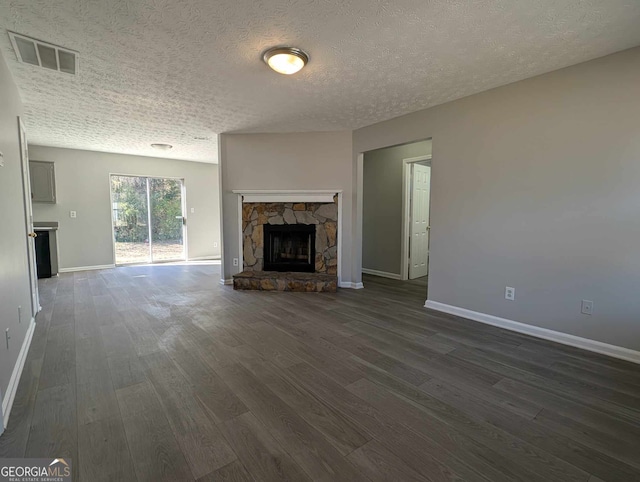 unfurnished living room featuring a fireplace, a textured ceiling, and dark hardwood / wood-style flooring