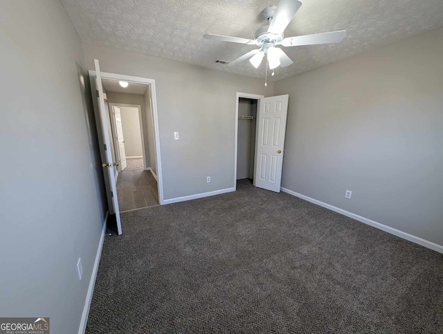 unfurnished bedroom featuring ceiling fan, dark carpet, a textured ceiling, and a closet