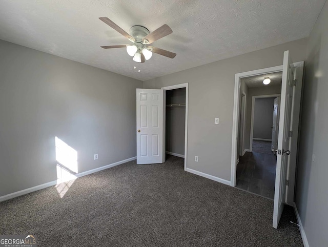 unfurnished bedroom with dark colored carpet, ceiling fan, a textured ceiling, and a closet