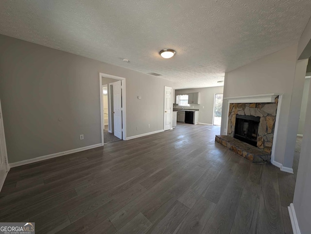 unfurnished living room with dark hardwood / wood-style floors, a fireplace, and a textured ceiling