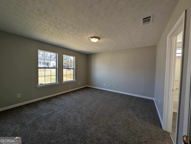 empty room with dark colored carpet and a textured ceiling