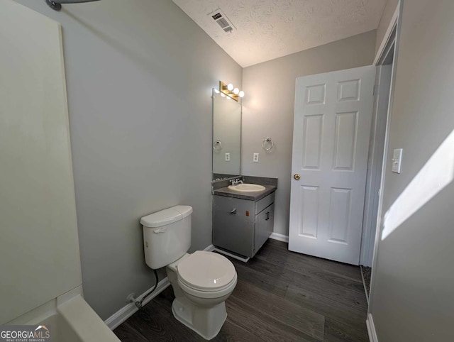 bathroom featuring vanity, wood-type flooring, a textured ceiling, and toilet