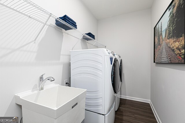 washroom featuring dark hardwood / wood-style flooring, washing machine and dryer, and sink