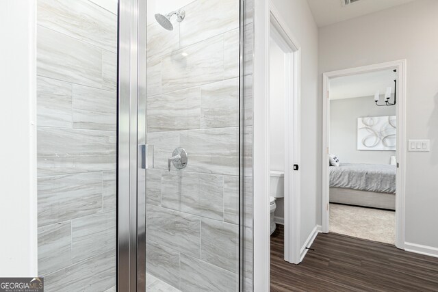 bathroom with hardwood / wood-style floors, toilet, and an enclosed shower