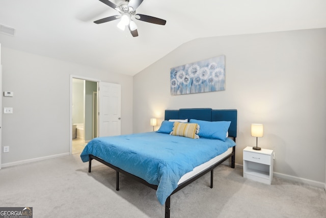 bedroom with ceiling fan, light colored carpet, ensuite bathroom, and vaulted ceiling