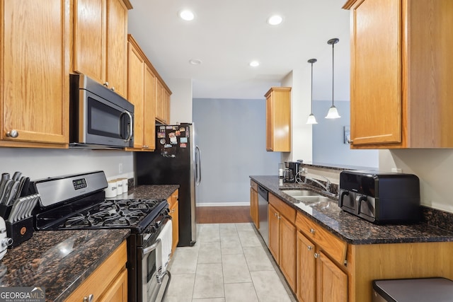 kitchen featuring sink, hanging light fixtures, dark stone counters, light tile patterned flooring, and appliances with stainless steel finishes