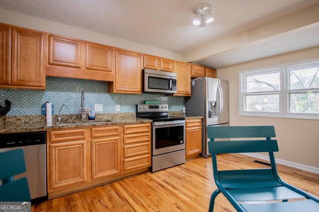 kitchen featuring backsplash, stainless steel appliances, stone countertops, and light wood-type flooring