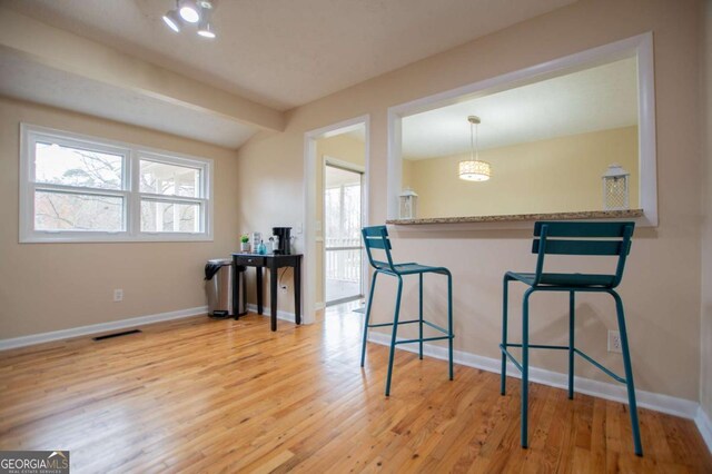 kitchen featuring kitchen peninsula, a breakfast bar, pendant lighting, and light hardwood / wood-style floors