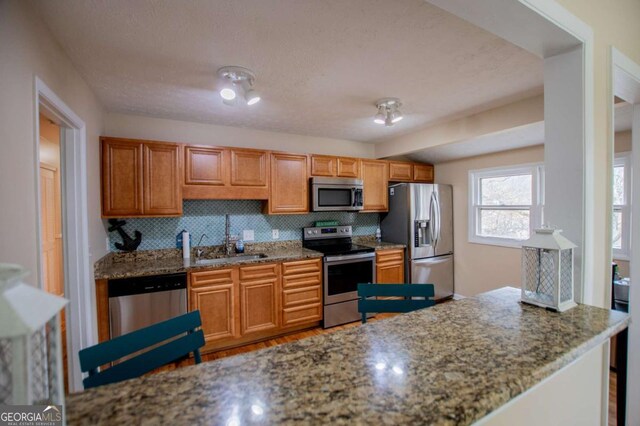 kitchen with light stone countertops, decorative backsplash, sink, and stainless steel appliances