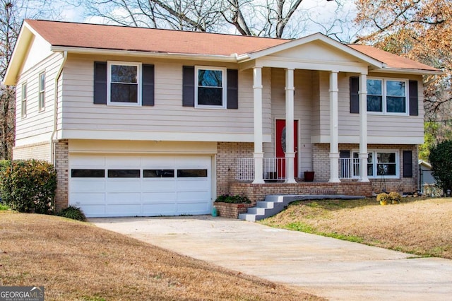 raised ranch with a porch, a garage, and a front yard