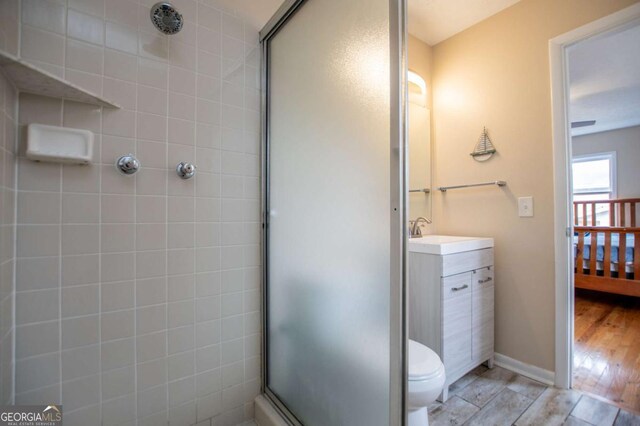 bathroom featuring toilet, hardwood / wood-style floors, vanity, and walk in shower