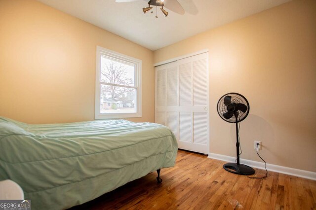 bedroom with ceiling fan, wood-type flooring, and a closet