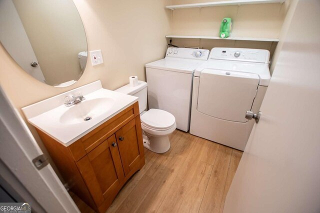 bathroom with washing machine and clothes dryer, vanity, wood-type flooring, and toilet