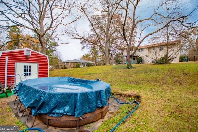 view of yard featuring a covered pool and a storage unit