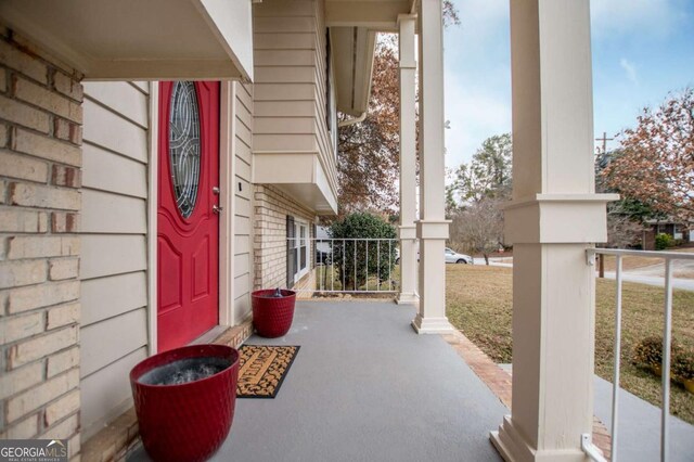 view of exterior entry featuring a yard and a porch