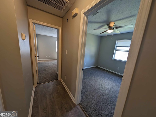 hallway featuring a textured ceiling and dark hardwood / wood-style floors