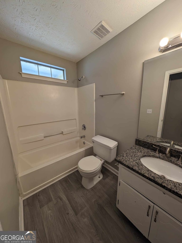 full bathroom with vanity, a textured ceiling,  shower combination, wood-type flooring, and toilet