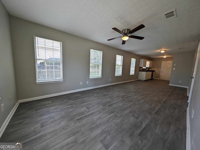 unfurnished living room with ceiling fan, dark wood-type flooring, and a textured ceiling