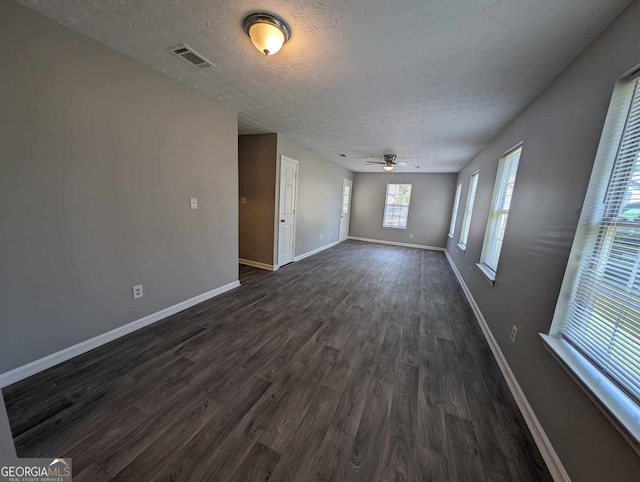 empty room with a textured ceiling, dark hardwood / wood-style flooring, and ceiling fan