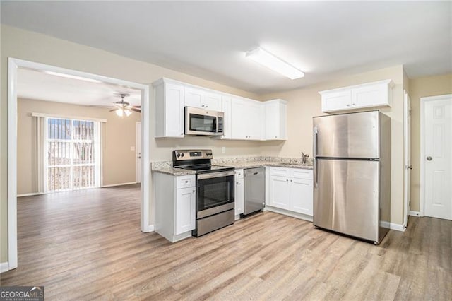 kitchen featuring appliances with stainless steel finishes, light stone counters, ceiling fan, light hardwood / wood-style floors, and white cabinetry