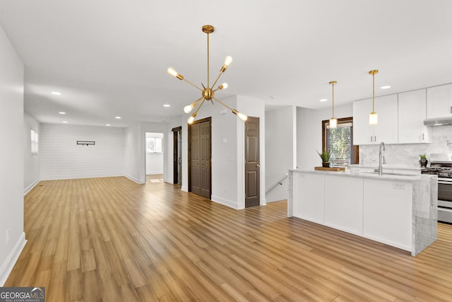 kitchen featuring gas stove, backsplash, pendant lighting, light hardwood / wood-style floors, and white cabinets