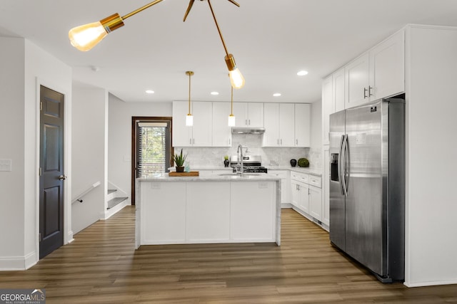 kitchen with stainless steel fridge, dark hardwood / wood-style flooring, a center island with sink, white cabinets, and hanging light fixtures