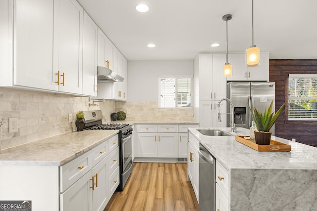 kitchen featuring sink, hanging light fixtures, stainless steel appliances, decorative backsplash, and white cabinets