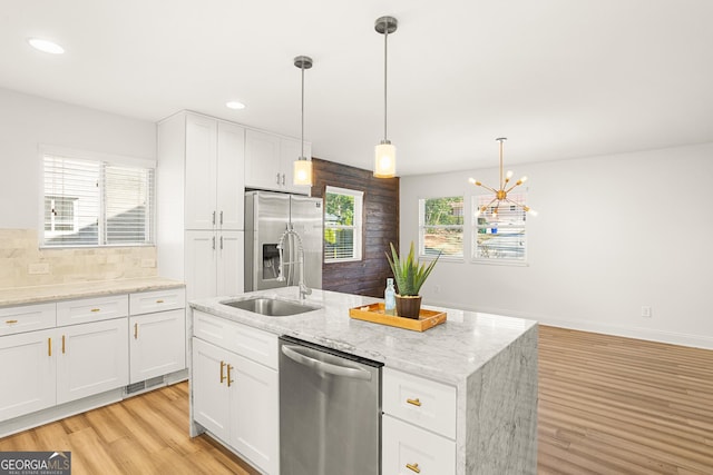 kitchen with white cabinets, pendant lighting, a center island with sink, and stainless steel appliances