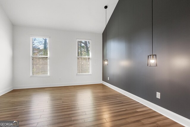 spare room featuring dark hardwood / wood-style floors and lofted ceiling