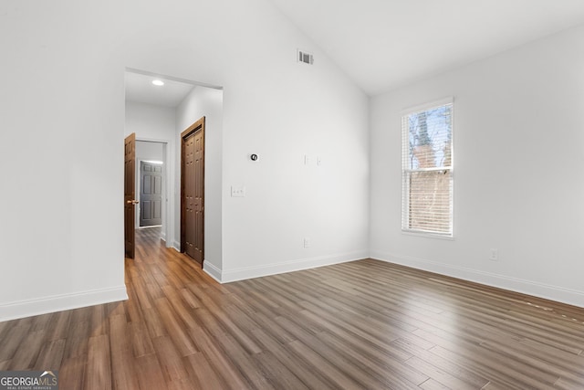 unfurnished room with hardwood / wood-style floors and vaulted ceiling