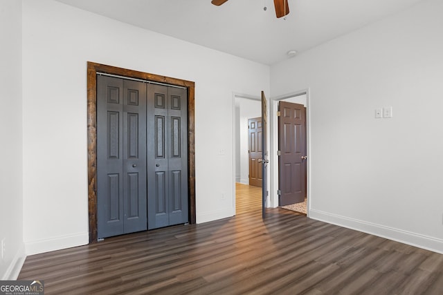 unfurnished bedroom featuring ceiling fan, a closet, and dark wood-type flooring