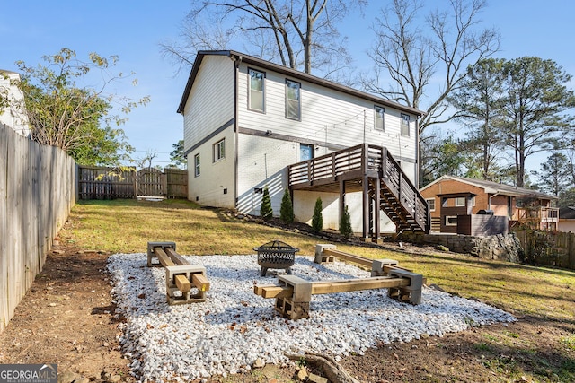 rear view of house with a lawn, an outdoor fire pit, and a wooden deck