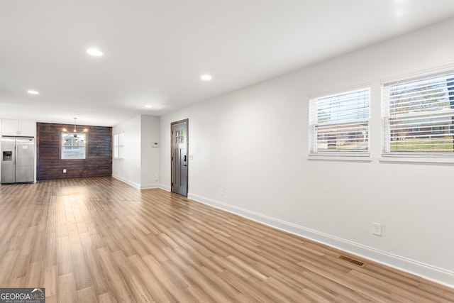 unfurnished living room featuring light hardwood / wood-style flooring and an inviting chandelier