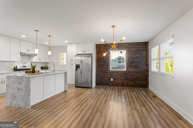 kitchen featuring light stone countertops, stainless steel appliances, decorative light fixtures, light hardwood / wood-style flooring, and white cabinets