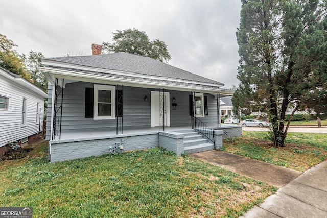 bungalow featuring covered porch and a front yard