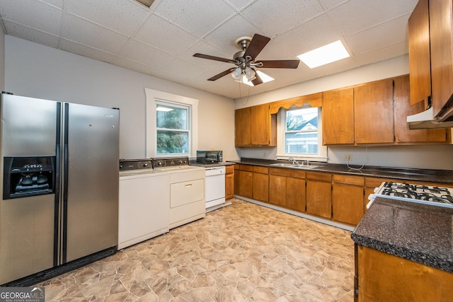 kitchen featuring stainless steel fridge, white dishwasher, ceiling fan, washer and clothes dryer, and sink