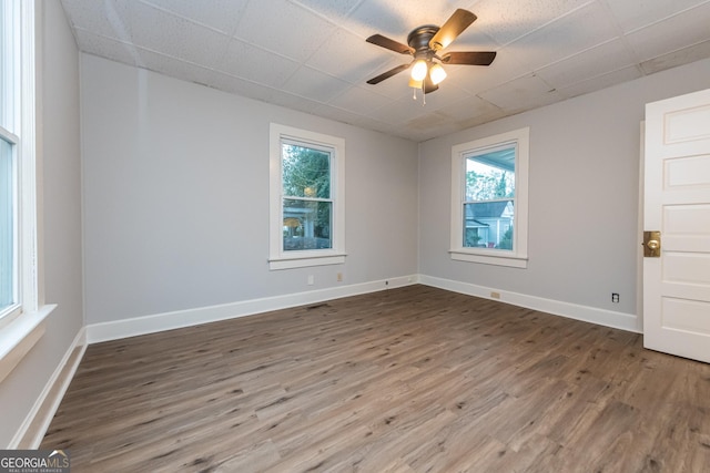 empty room featuring hardwood / wood-style flooring, ceiling fan, and a healthy amount of sunlight