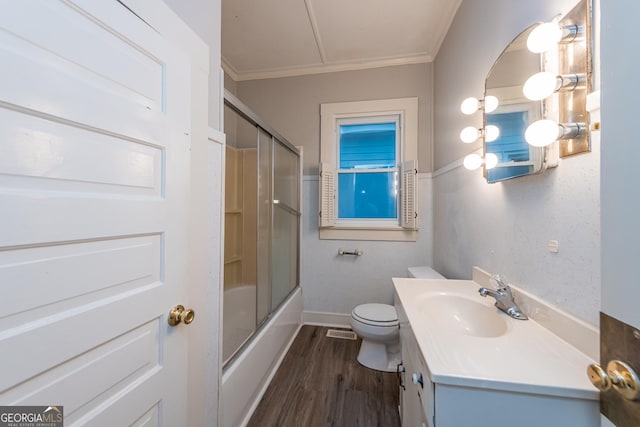 full bathroom with ornamental molding, vanity, enclosed tub / shower combo, hardwood / wood-style floors, and toilet