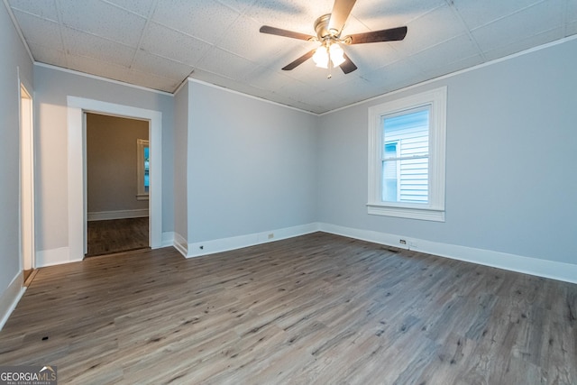 empty room with ceiling fan, wood-type flooring, and ornamental molding