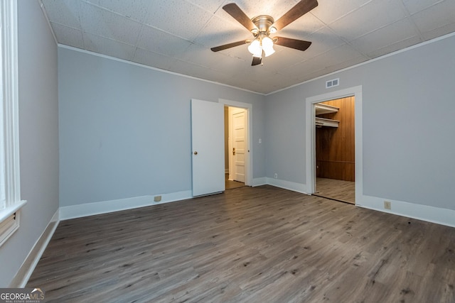 unfurnished bedroom with hardwood / wood-style flooring, ceiling fan, a walk in closet, and a closet