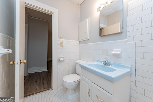 bathroom with tile patterned floors, vanity, toilet, and tile walls