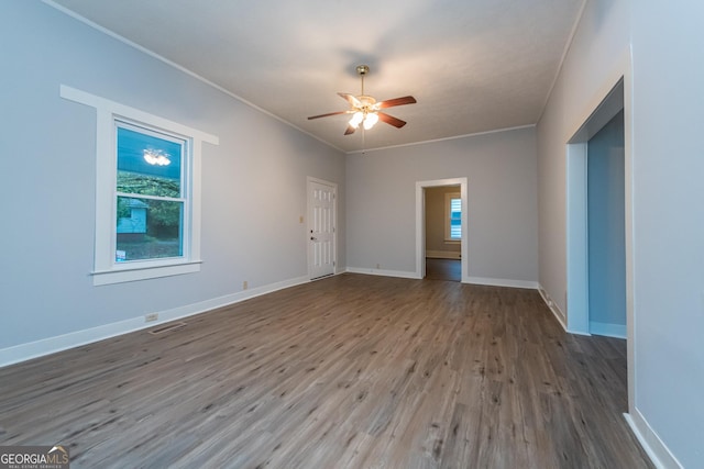 unfurnished room with a wealth of natural light, ceiling fan, wood-type flooring, and ornamental molding